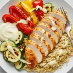 Sliced air fryer chicken breast served over quinoa with grilled vegetables and lemon tahini dressing